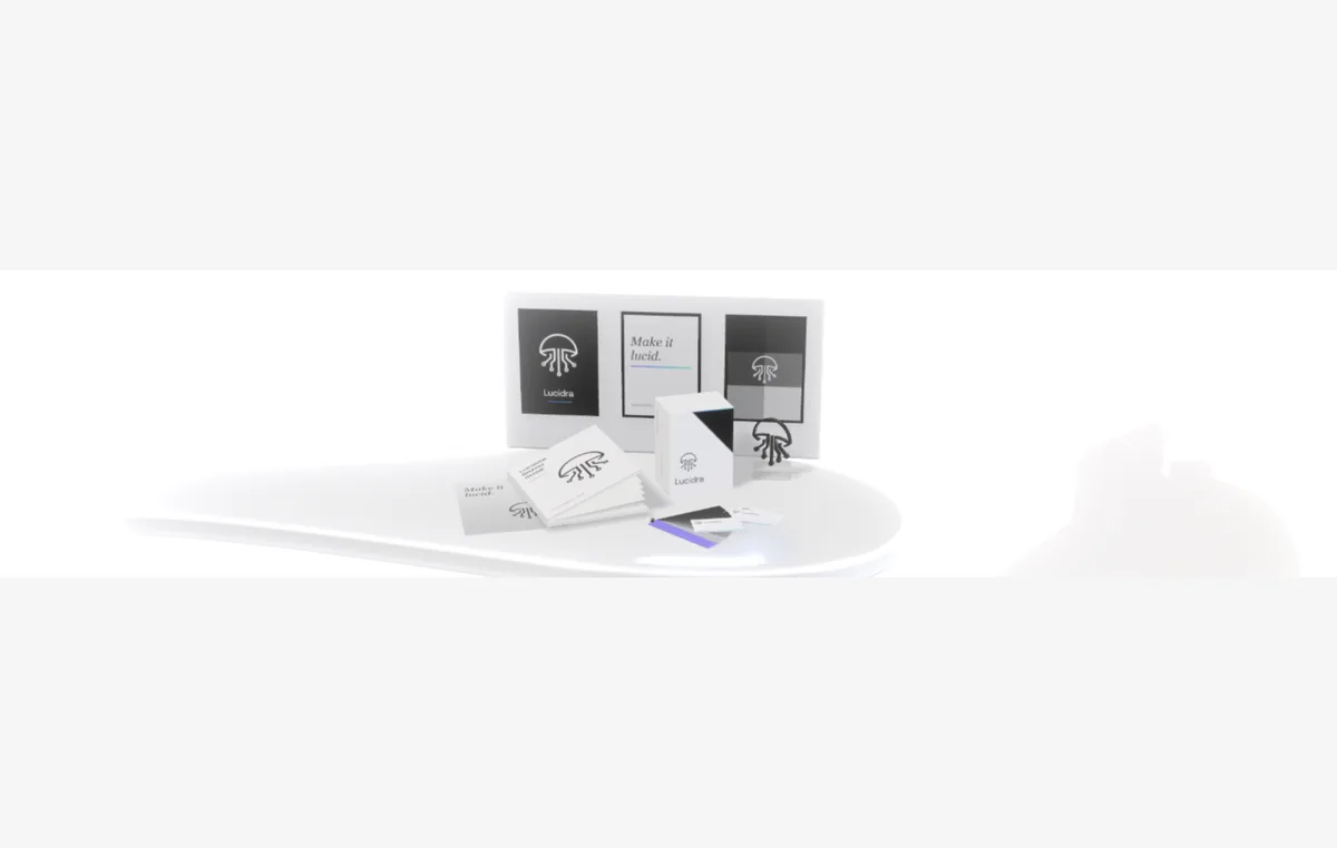 A brand guide floating open above a desk, product boxes with the logo, a colour fan and business cards, with a poster wall behind